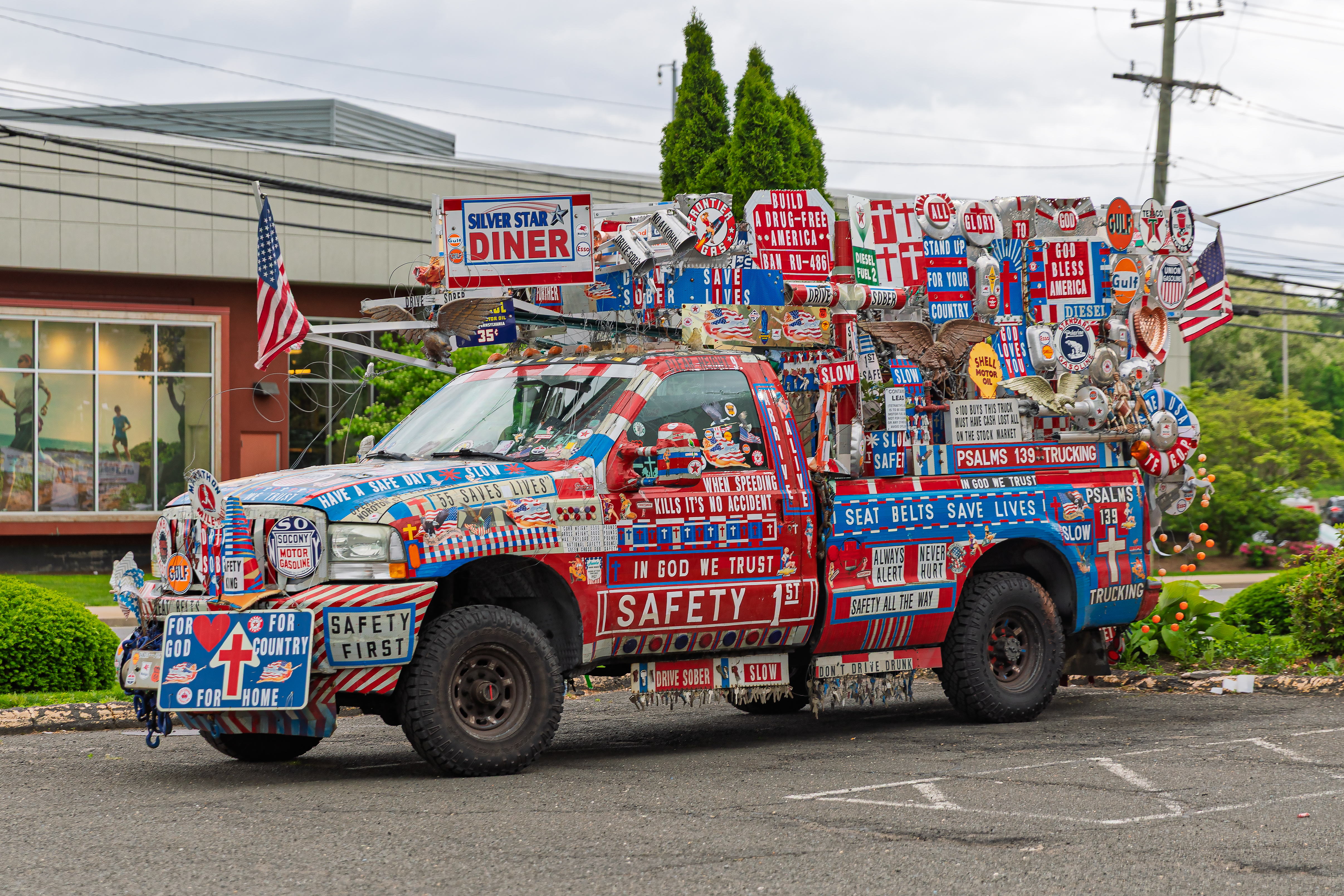 Pickup truck covered in patriotic and religious signs parked outside a diner